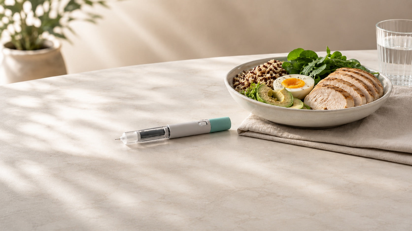 Abnehmspritze neben einer proteinreichen Mahlzeit mit Hähnchen, Ei, Quinoa, Avocado und grünem Salat auf einem hellen Tisch.