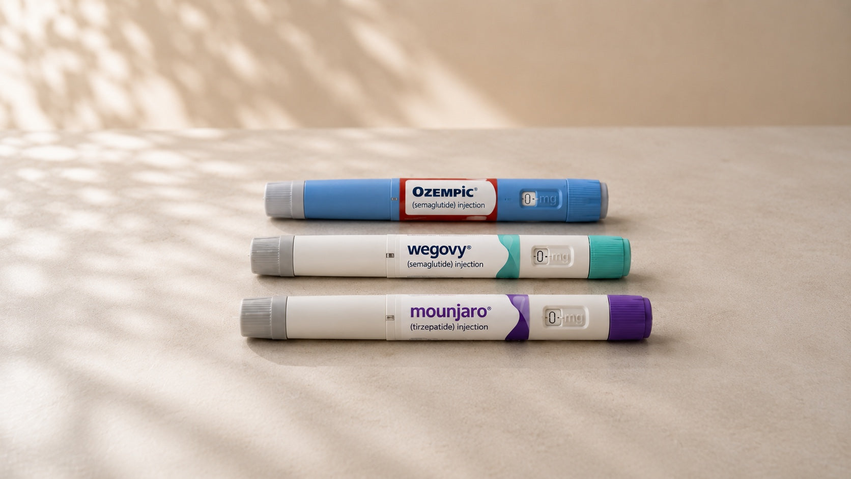 Drei beispielhaft dargestellte Injektionspens für Ozempic, Wegovy und Mounjaro auf einem hellen Tisch in minimalistischer Editorial-Inszenierung.