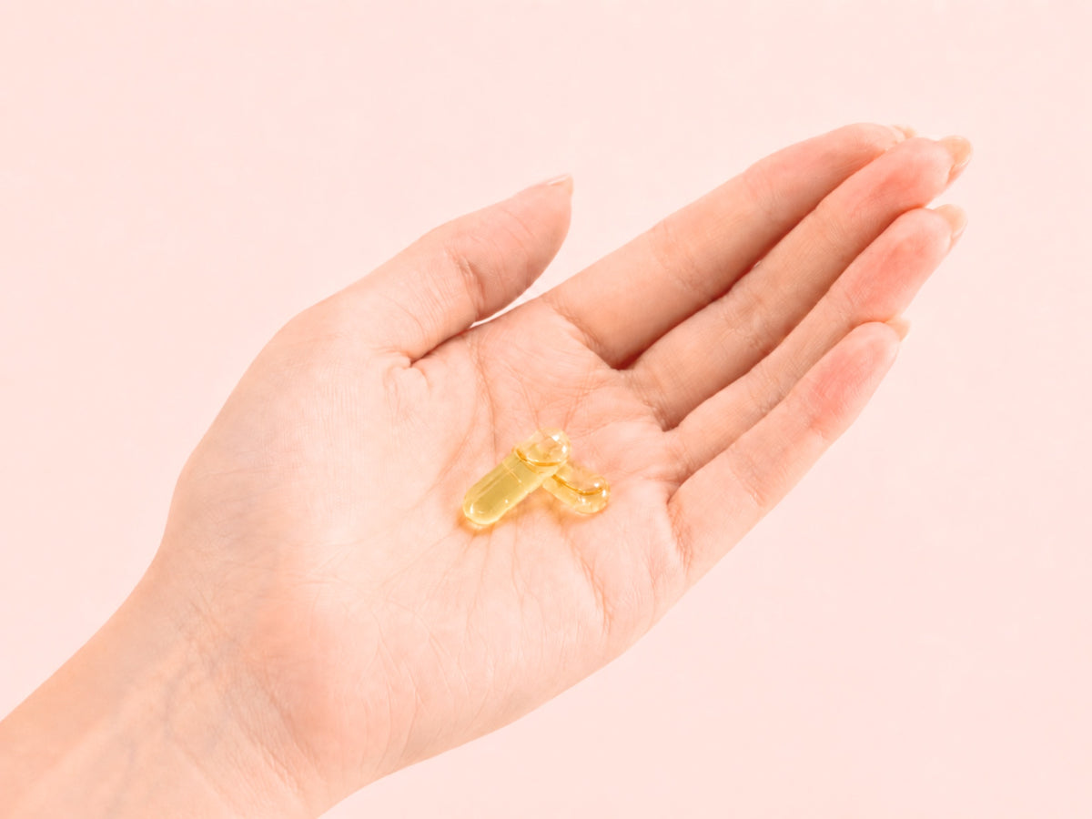 Zwei goldene PULSE Omega-3 Liquid-Kapseln von Fifty Five in einer geöffneten Hand